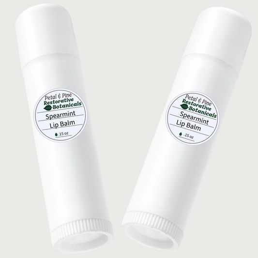 Two white lip balm tubes with Petal & Pine Spearmint labels on a light gray background